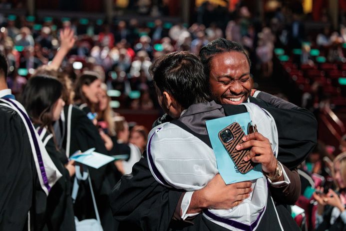 Two graduates hugging each other with joy on graduation day