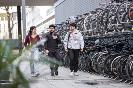 Three students walking past a bike shed
