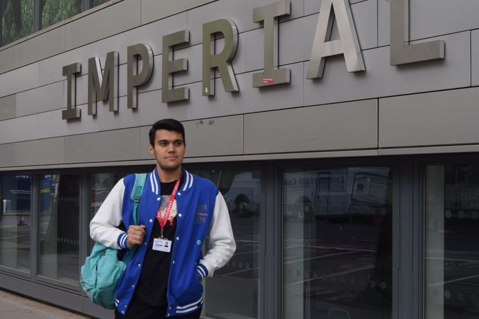 A student standing in front of Imperial building, looking at the camera.