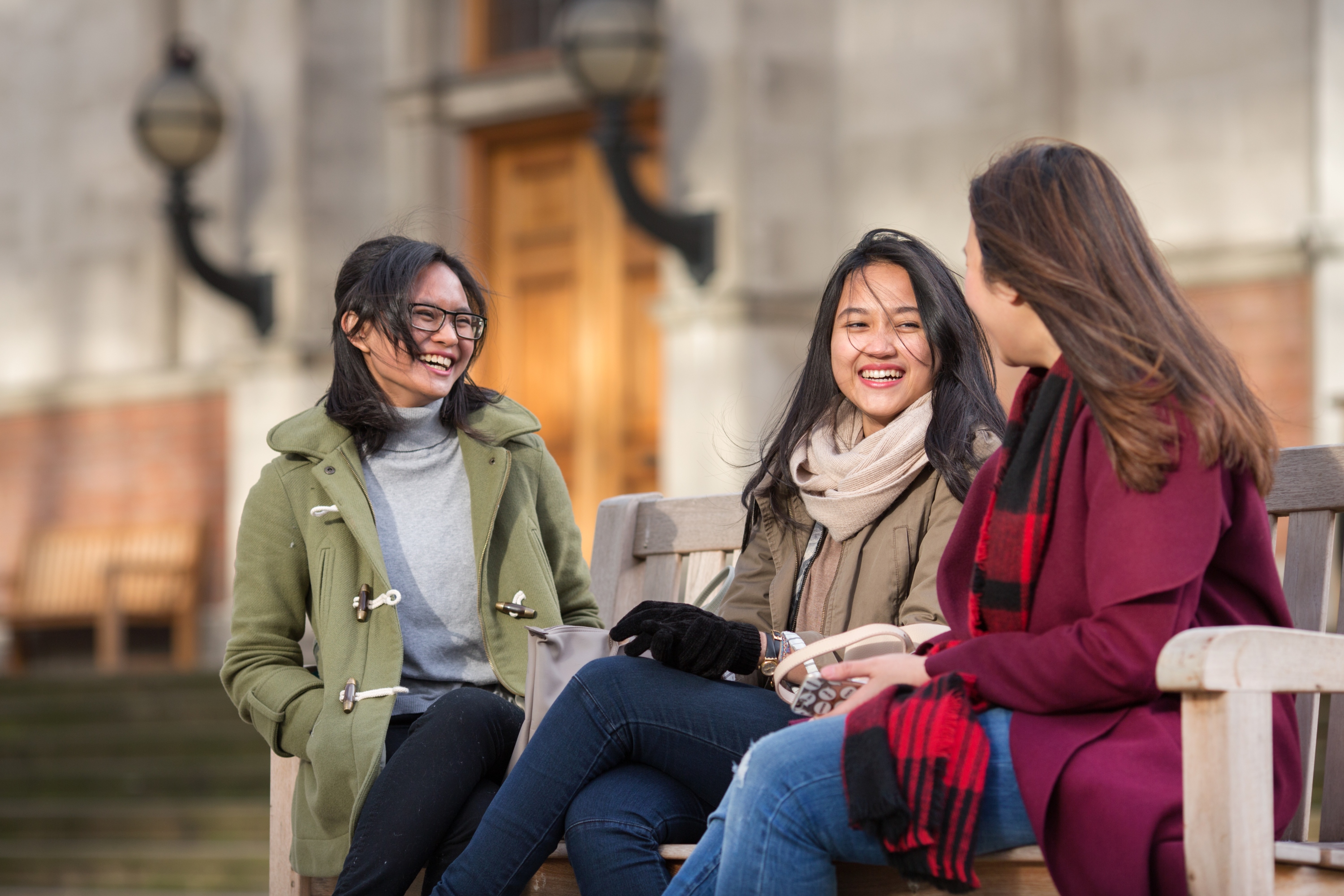 Three female students sat under the Queens Tower