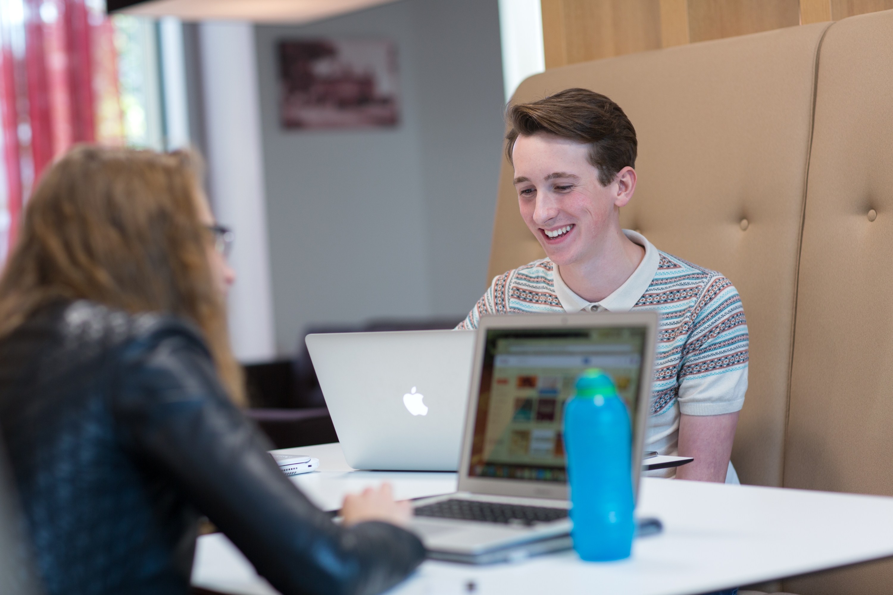 Two students sat at a table on laptops