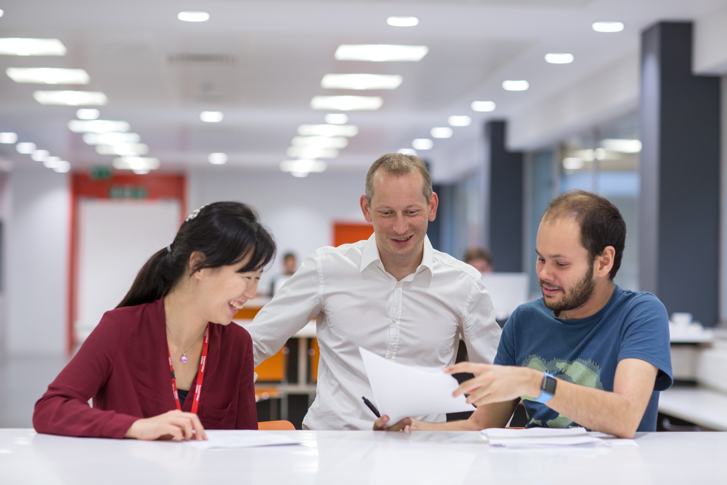 Three people looking at a sheet of paper