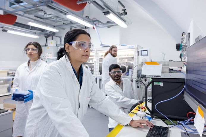 A researcher in a lab coat working on a computer