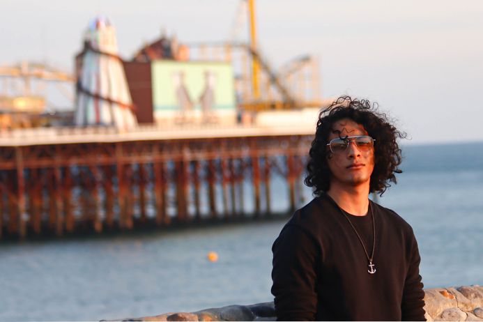 portrait of a male student in front of a pier leading out to sea