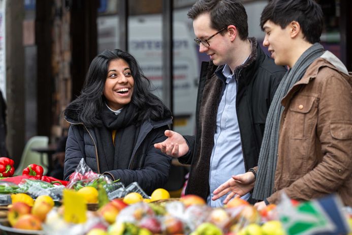 Three students standing by produce outside in Fulham Market
