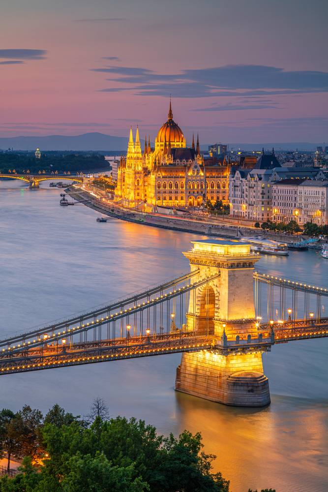 Aerial cityscape image of Budapest with Szechenyi Chain Bridge and parliament building during summer sunset